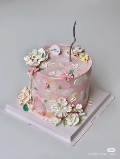 a pink cake with flowers on it sitting on top of a table