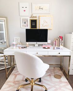 a white desk topped with a computer monitor next to a gold framed wall mounted art