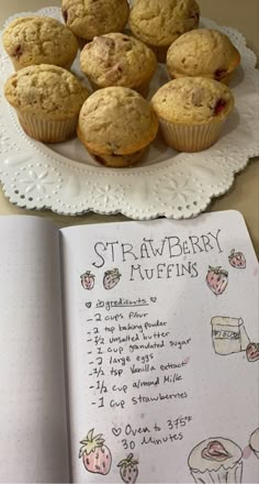 some muffins are sitting on a plate next to a recipe book and cupcakes