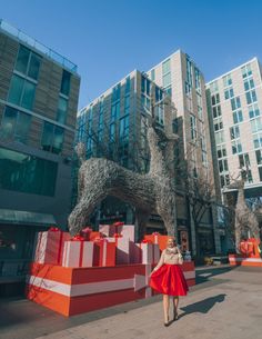 a woman in a red dress standing next to a statue of a dog and presents