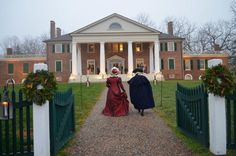 two women in red dresses are walking towards a large house