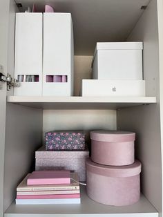 the shelves are filled with boxes, books and other decorative items in pinks and whites