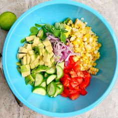 a blue bowl filled with different types of veggies and sliced up corn on the cob