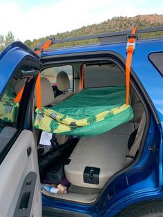 the back end of a blue truck with a sleeping bag in it's trunk