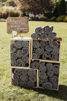 a stack of rolled up towels sitting on top of a lush green field next to a wooden sign