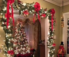 a christmas tree decorated with red bows and lights in a living room next to a doorway