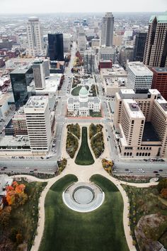 an aerial view of a city with lots of tall buildings and green grass in the foreground