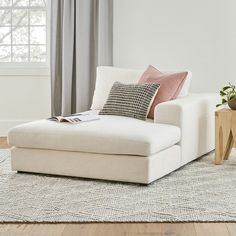 a white couch sitting on top of a wooden floor next to a table and window