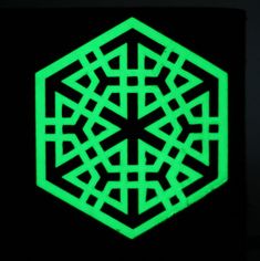 a black and green hexagonal design on the side of a building at night