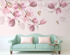 a couch sitting in front of a wall with pink flowers painted on it's walls