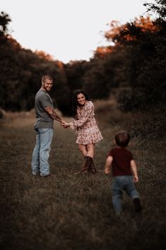 a man and woman holding hands while standing in the grass