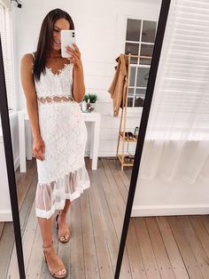 a woman taking a selfie in front of a mirror wearing a white lace dress