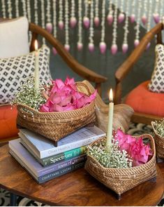 two wicker baskets filled with pink flowers on top of a table next to books