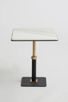 a table with a marble top and brass base on a black stand against a white background