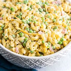 a bowl filled with macaroni and peas on top of a blue table cloth