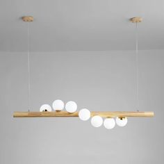 an overhead light fixture with five white balls hanging from it's wooden beam in a living room