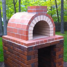 an outdoor brick pizza oven sitting in the grass