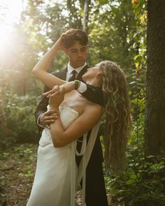 a young man and woman are dancing in the woods