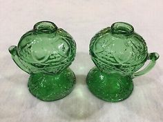 two green glass vases sitting next to each other on a white tableclothed surface