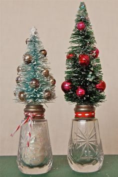 two small christmas trees sitting on top of glass vases