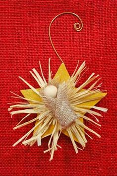 an ornament made out of paper on a red cloth with gold and white decorations