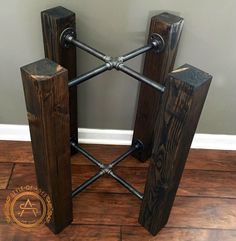 two wooden stands with iron bars on them sitting on a wood floor in front of a gray wall