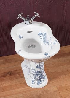 a white sink sitting on top of a wooden floor next to a red and purple wall