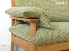 a green chair with two pillows on it's back and the seat upholstered