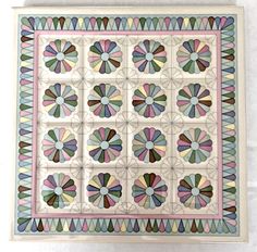 an artisticly designed tile is displayed on a white surface with blue, green, pink and brown colors