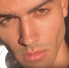 a close up of a person wearing a ring on his nose and looking at the camera