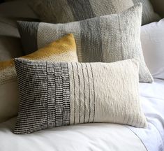 four pillows are stacked on top of each other, one is yellow and the other is gray