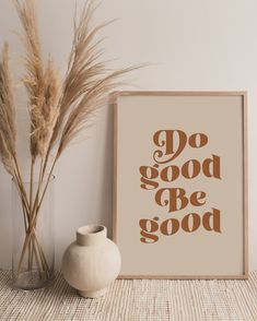 there is a vase with some dry grass in it next to a poster that says do good be good