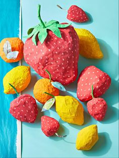 some strawberries and oranges are on a blue surface with white polka dot paper