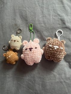 three crocheted animal keychains sitting on top of a gray cloth covered bed