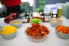 bowls filled with different types of food on top of a white tablecloth covered table