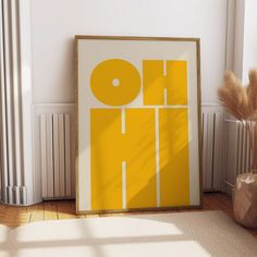 a yellow and white poster sitting on top of a wooden floor next to a vase