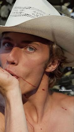 a shirtless man wearing a white cowboy hat