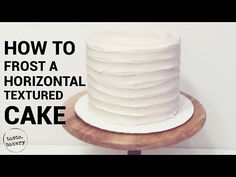 a white frosted cake sitting on top of a wooden stand with the words how to frost a horizontal textured cake