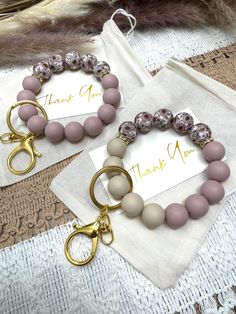 two bracelets with pink beads and gold handles on top of a lace doily