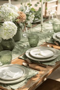 the table is set with plates, silverware and flowers in vases on it