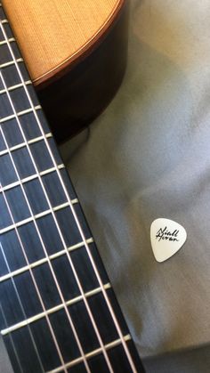 a guitar pick sitting on top of a gray cloth next to a wooden necktie