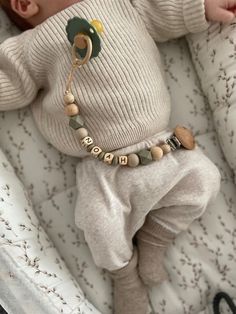 a baby laying in a crib wearing a sweater and pants with beads on it