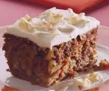 a piece of carrot cake with white frosting on a pink tableclothed place mat