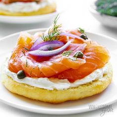 an assortment of appetizers are displayed on small white plates, including smoked salmon and cream cheese