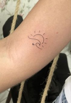 a woman's arm with a sun and moon tattoo on the left side of her arm