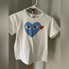 a white t - shirt with a blue heart and two red hearts on the front