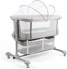 a baby crib with mosquito netting on the top and wheels, in front of a white background