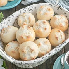 a bowl filled with rolls sitting on top of a wooden table