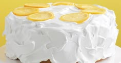 a cake with frosting and lemons on top sitting on a white platter