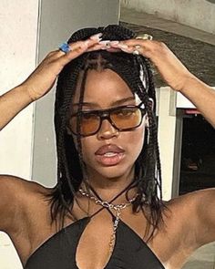 a woman wearing glasses and a halter top is holding her hair in the air